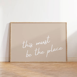 neutral beige background with white cursive this must be the place print horizontal