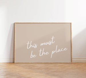 neutral beige background with white cursive this must be the place print horizontal