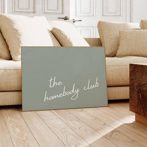 sage green background with white script typography the homebody club horizontal wall art