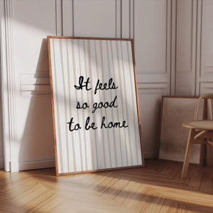 it feels so good to be home quote in black handwriting font on neutral beige stripe background, vertical orientation wall art