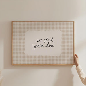 so glad you're here quote in hand drawn black script typography on beige gingham background horizontal wall art